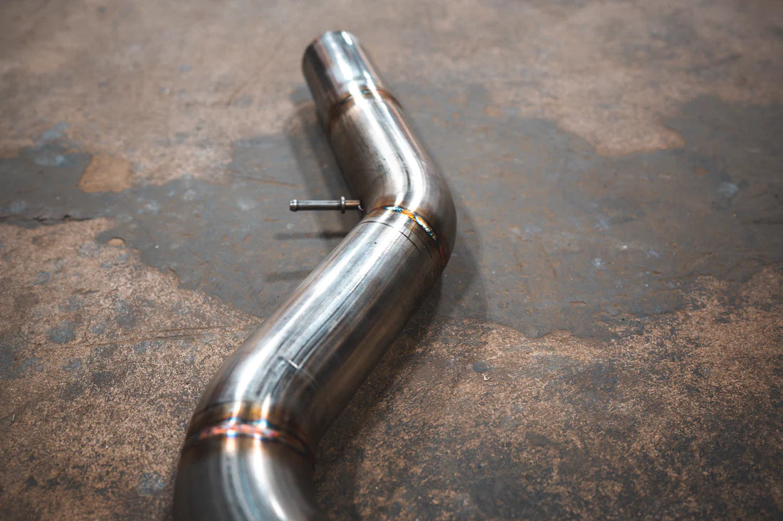 A close up view of Valvetronic Designs Valved Axleback Exhaust System's pipes on the ground (for BMW G20/G22 330i/430i). 