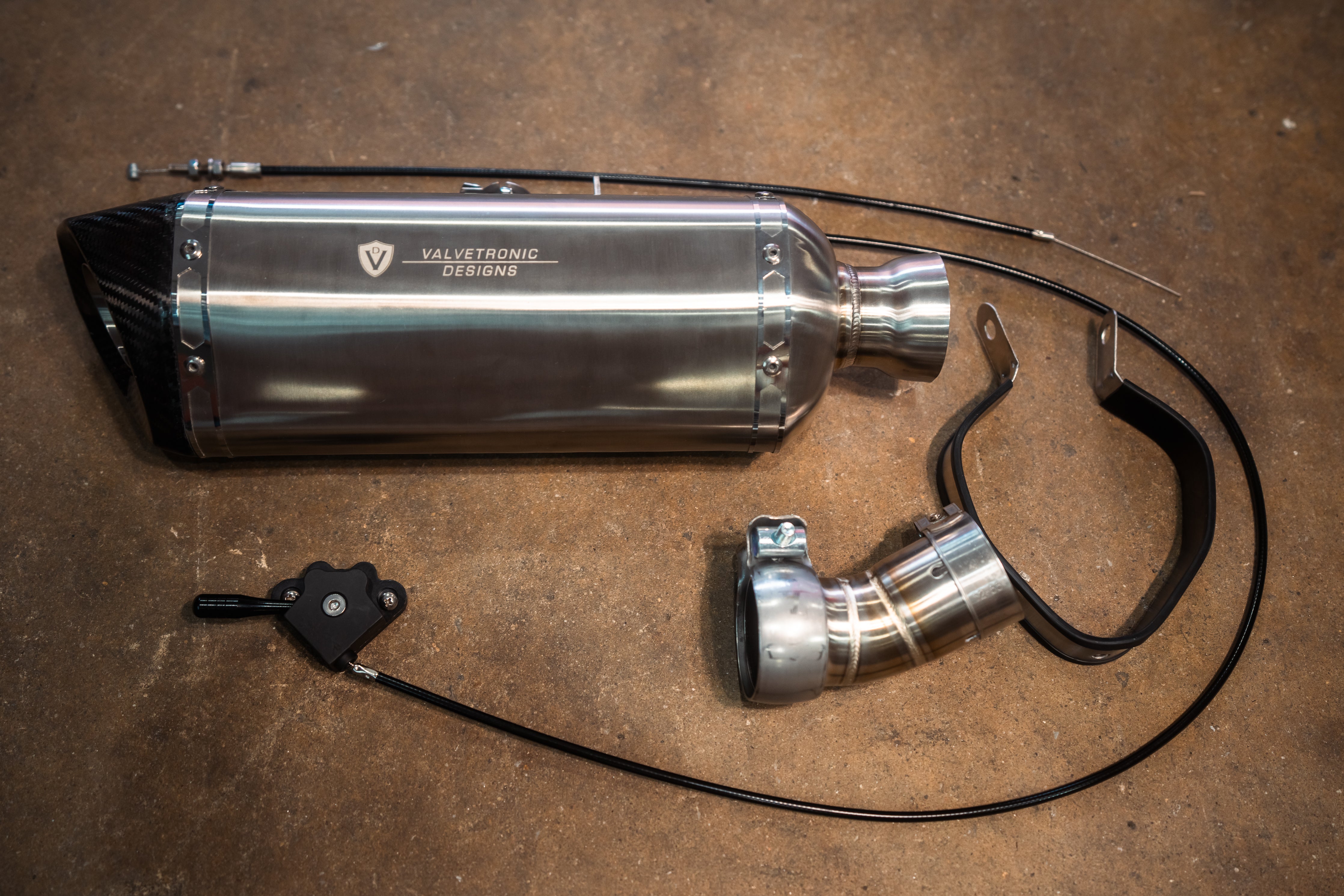 Valvetronic Designs Motorcycle Valved Muffler manufacturer gallery: muffler and curved adapter with control lever in the lower left
