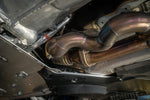 A close up view of Valvetronic Designs Valved Sport Exhaust System fitted on a lifted blue car from beneath (for BMW G87 M2).