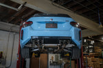 A overview of Valvetronic Designs Valved Sport Exhaust System fitted on a lifted blue car from behind (for BMW G87 M2). 