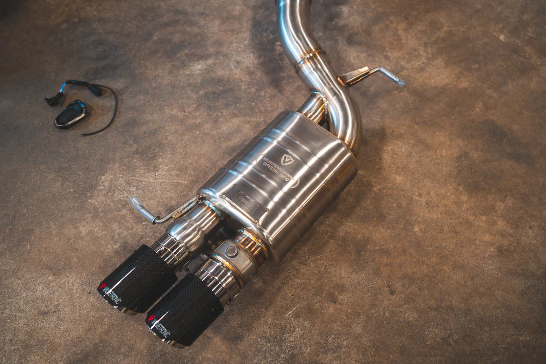 A close overview of Valvetronic Designs Valved Sport Exhaust System's exhaust and 1x1 Carbon Fiber exhaust tips on the ground (for BMW F10 M5 / F12 M6 / F06 M6).