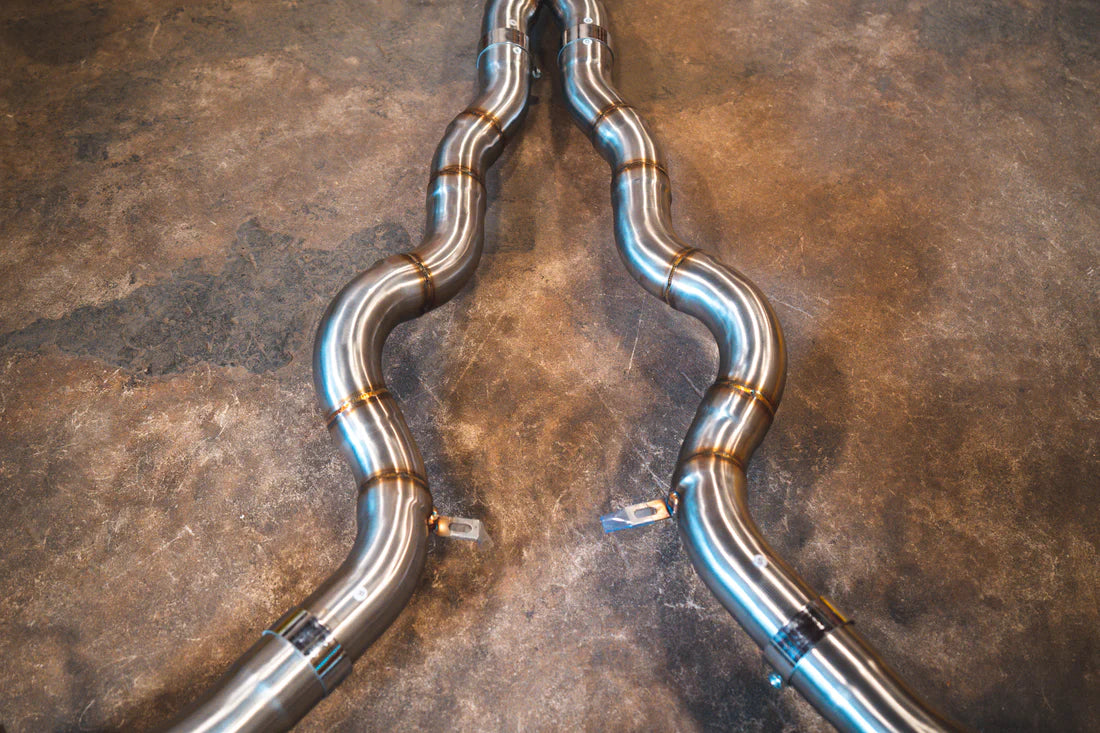 A close overview of Valvetronic Designs Valved Sport Exhaust System's pipes on the ground (for BMW F10 M5 / F12 M6 / F06 M6). 