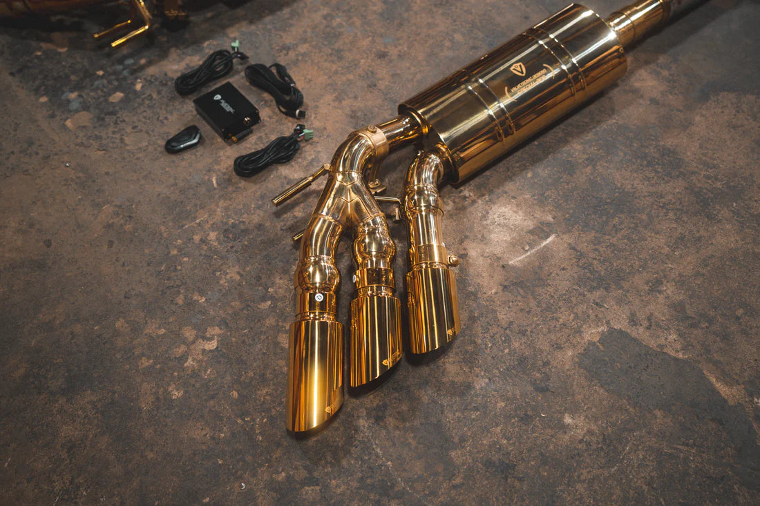 A close up view of Valvetronic Designs Valved Sport Exhaust System's exhaust tips with valve controllers and wires on the ground (for Mercedes Benz G-Wagon G550, G63 / Squared).