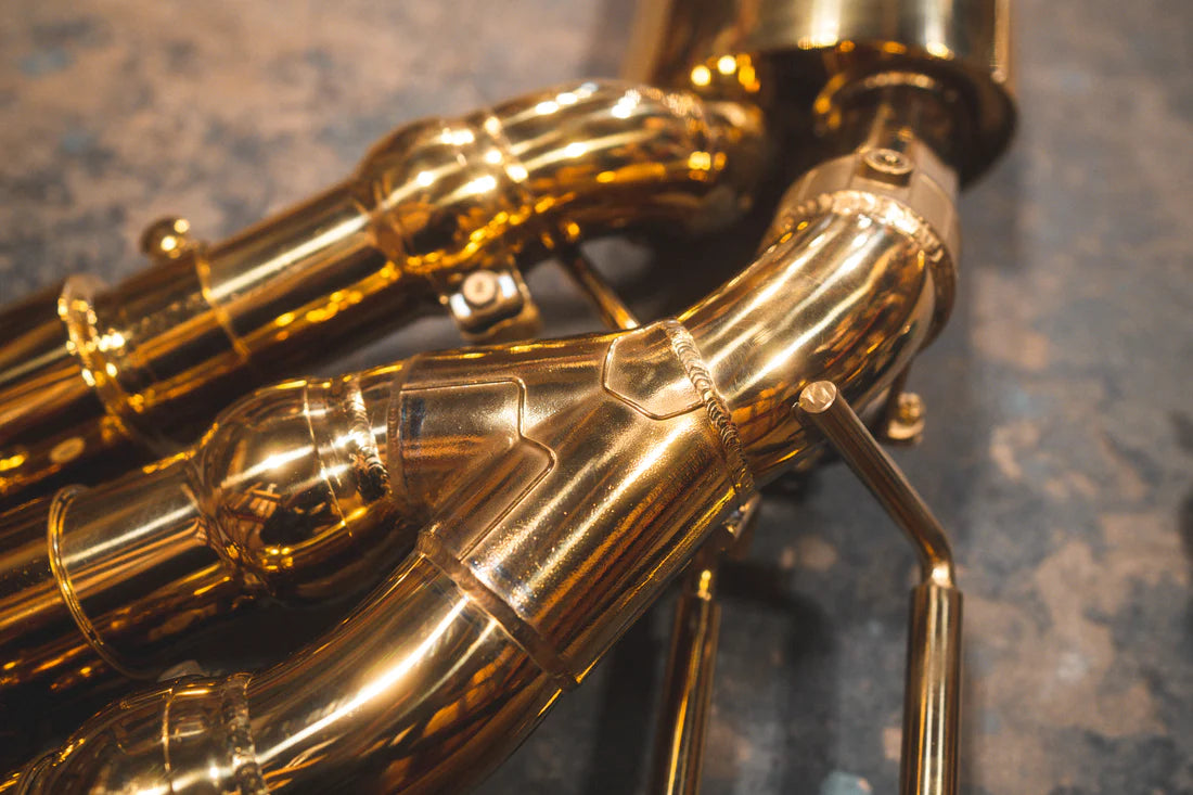 A close up view of Valvetronic Designs Valved Sport Exhaust System's pipes on the ground (for Mercedes Benz G-Wagon G550, G63 / Squared).