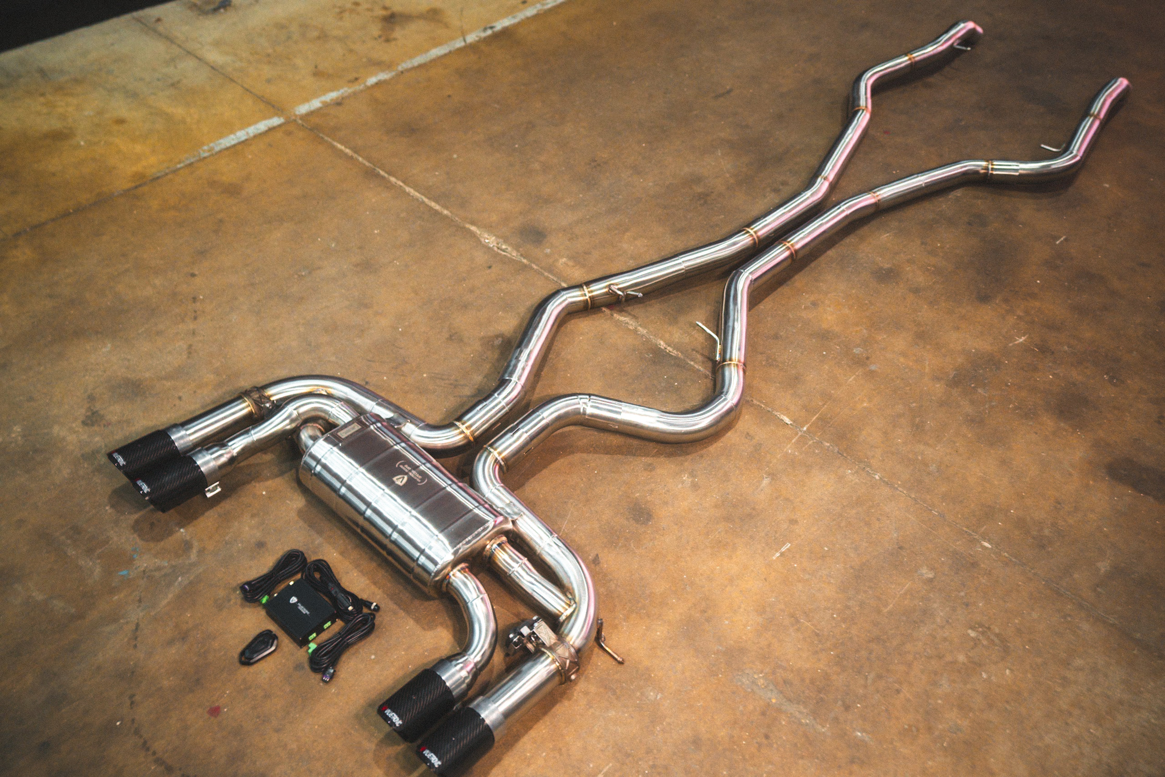 Valvetronic Designs Exhaust BMW F85 X5M / F86 X6M manufacturer gallery: complete exhaust laid diagonally across the workshop floor