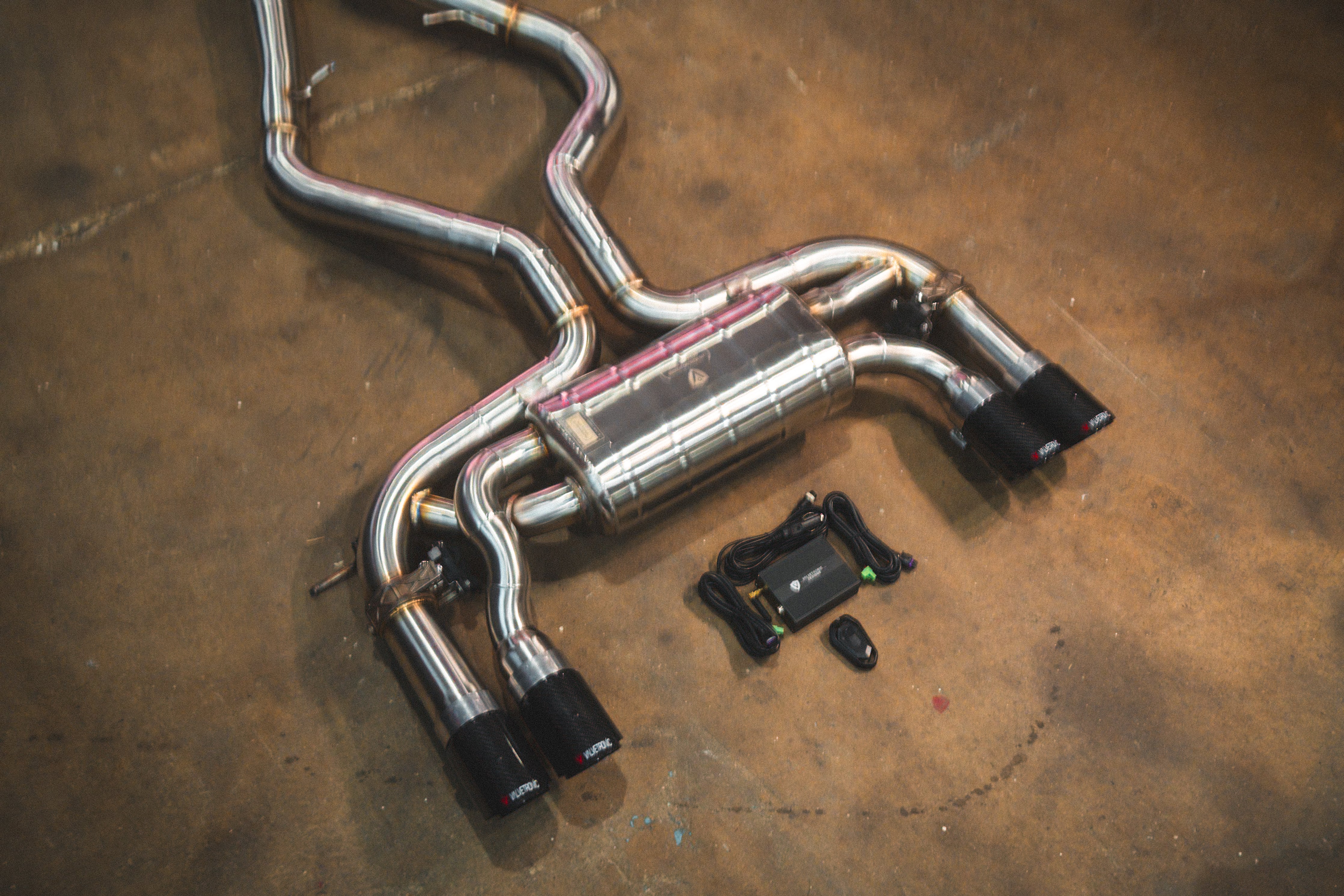 Valvetronic Designs Exhaust BMW F85 X5M / F86 X6M manufacturer gallery: rear muffler, curved branches and control kit viewed diagonally
