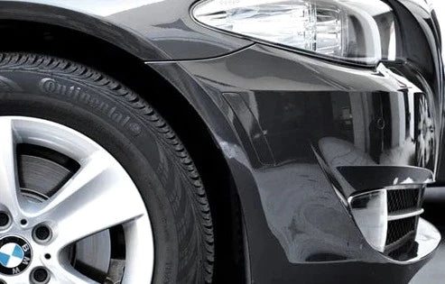 A close up view of AUTOTECKNIC PAINTED FRONT BUMPER REFLECTORS - BMW F10 M5 2011-2016 fitted on a black car