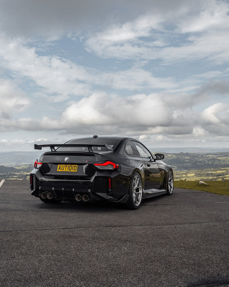 wide rear view of TRE Carbon Fiber Rear Bumper Winglets for BMW G87 M2 TR87 2023+ fitted inside a car