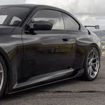 wide side view of TRE Carbon Fiber Side Skirts for BMW G87 M2 TR87 2023+ fitted inside a car