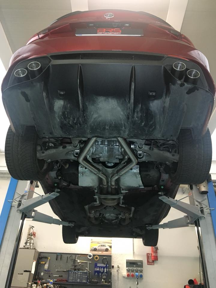 Red Giulia Quadrifoglio on a lift showing Capristo connecting pipes from below
