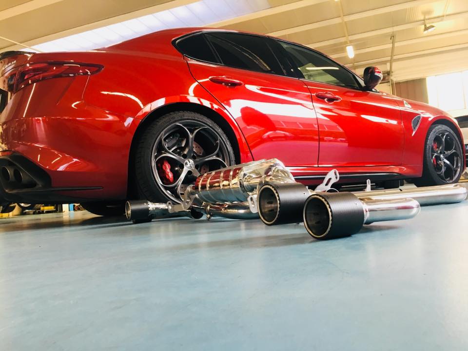 Capristo exhaust laid on the floor beside a red Alfa Romeo Giulia Quadrifoglio