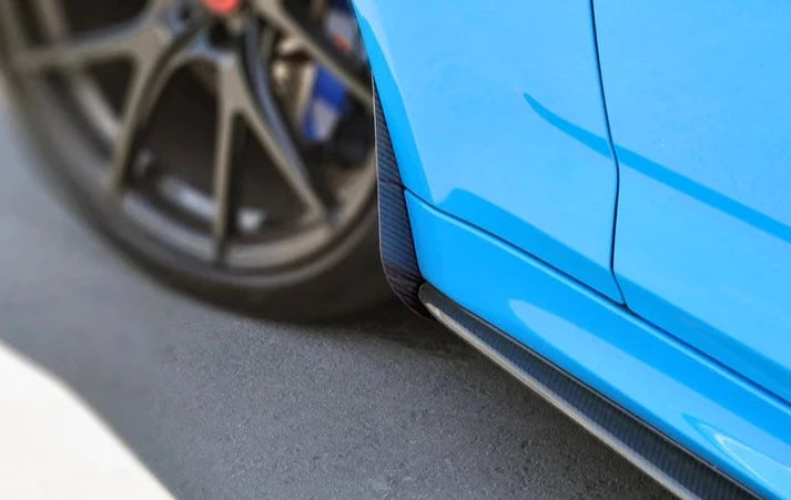 A close up view of AUTOTECKNIC CARBON FIBER FRONT SPLASH GUARDS - BMW F90 M5 2017+ fitted on a blue car