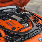 Engine bay of an orange F80 M3 with the VRSF front facing intakes fitted, hood open