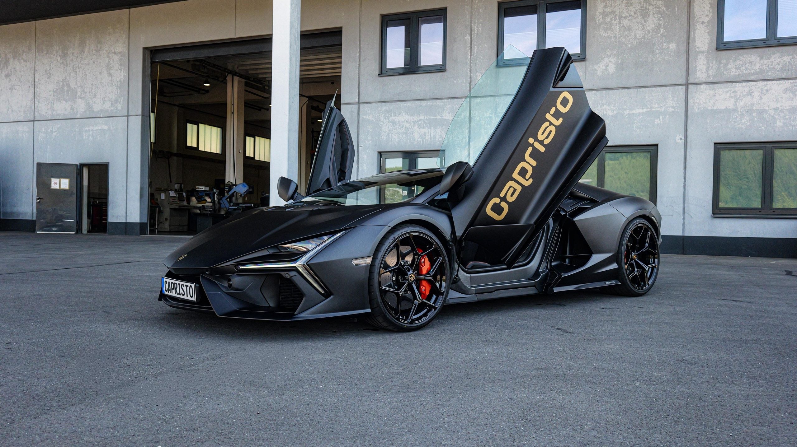 Matte grey Lamborghini Revuelto with Capristo door graphics outside the factory