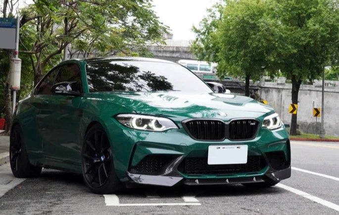 A front wide view of AUTOTECKNIC DRY CARBON PERFORMANTE AERO SPLITTERS - BMW F87 M2 COMPETITION 2018+ fitted on a olive green car