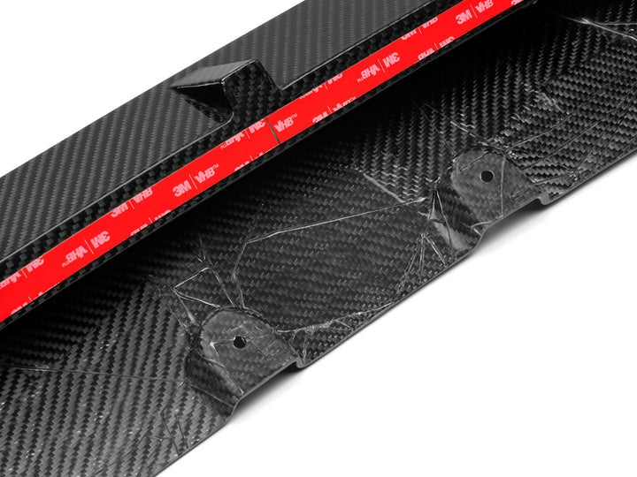 A close up view of AUTOTECKNIC PERFORMANCE DRY CARBON FRONT LIP SET - BMW F95 X5M 2019+ with white background