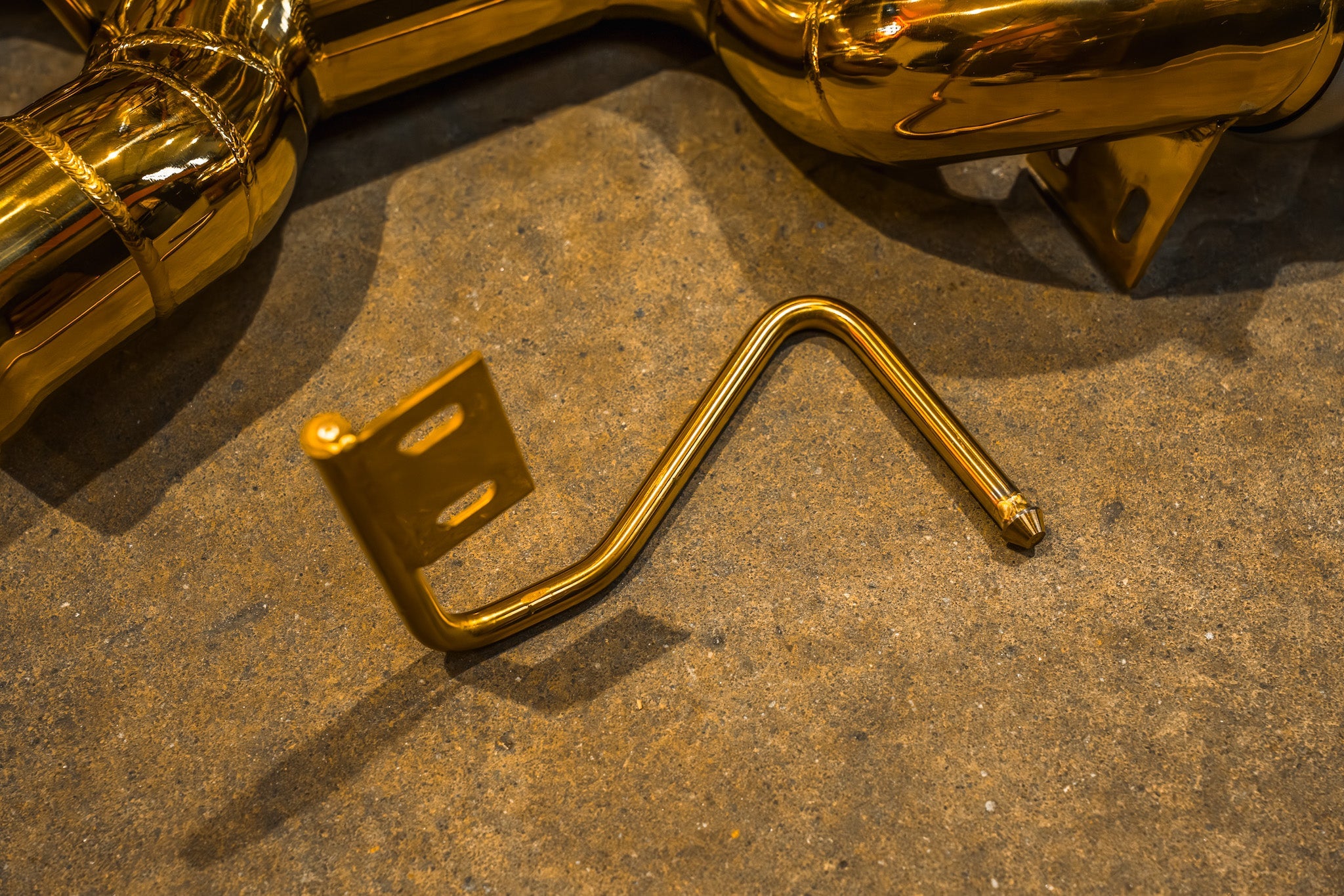 Valvetronic Designs F1 Exhaust McLaren 650S / MP4-12C manufacturer gallery: bent mounting bracket beside the gold-colored tubes