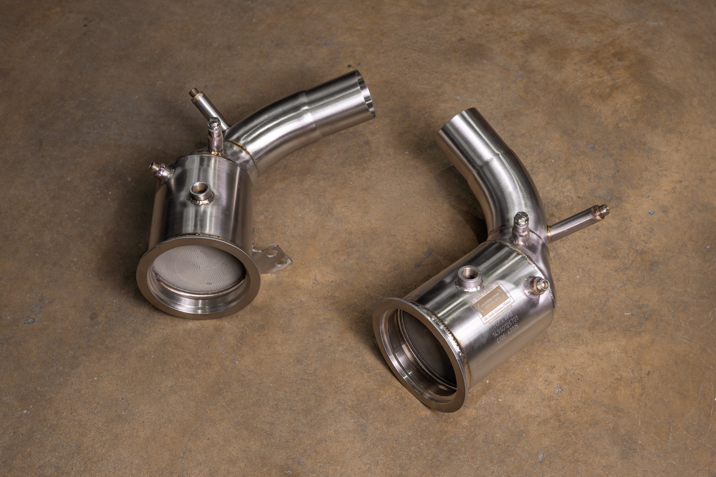 Valvetronic Designs 400 Cell Downpipes Porsche 992 Turbo / S manufacturer gallery: pair of downpipes laid diagonally with their inlet flanges visible