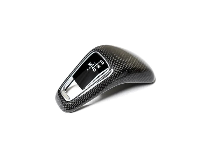 A front view of AUTOTECKNIC CARBON FIBER GEAR SELECTOR COVER - PORSCHE 9Y0/9Y0.2 CAYENNE 2019+ with white background