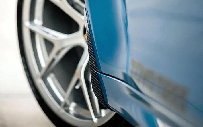 A close up view of AUTOTECKNIC CARBON FIBER FRONT SPLASH GUARDS - BMW F87 M2 | M2 Competition 2016+ fitted on a blue car