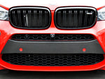 A close up view of the front of a red car fitted with AUTOTECKNIC DRY CARBON FIBER BUMPER TRIM - BMW F85 X5M | F86 X6M 2015-2021