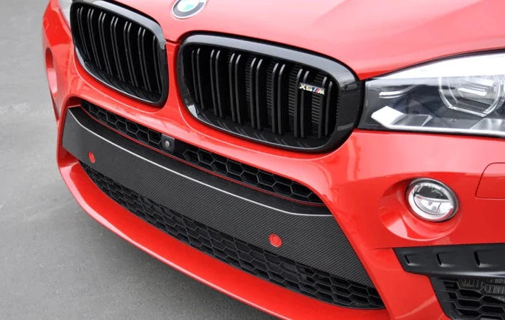 A side close up view of a red car fitted with AUTOTECKNIC DRY CARBON FIBER BUMPER TRIM - BMW F85 X5M | F86 X6M 2015-2021