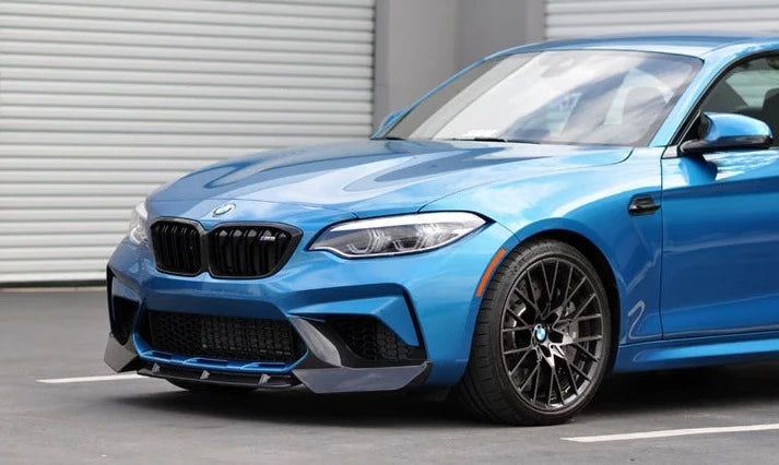 A side close up view of a blue car fitted with AUTOTECKNIC DRY CARBON FIBER CENTER FRONT LIP - BMW F87 M2 COMPETITION 2018+