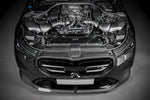Black carbon fiber turbo inlet pipes installed in BMW M5 engine bay with hood open showing complete engine compartment - Eventuri turbo inlet for BMW G90 G99 M5