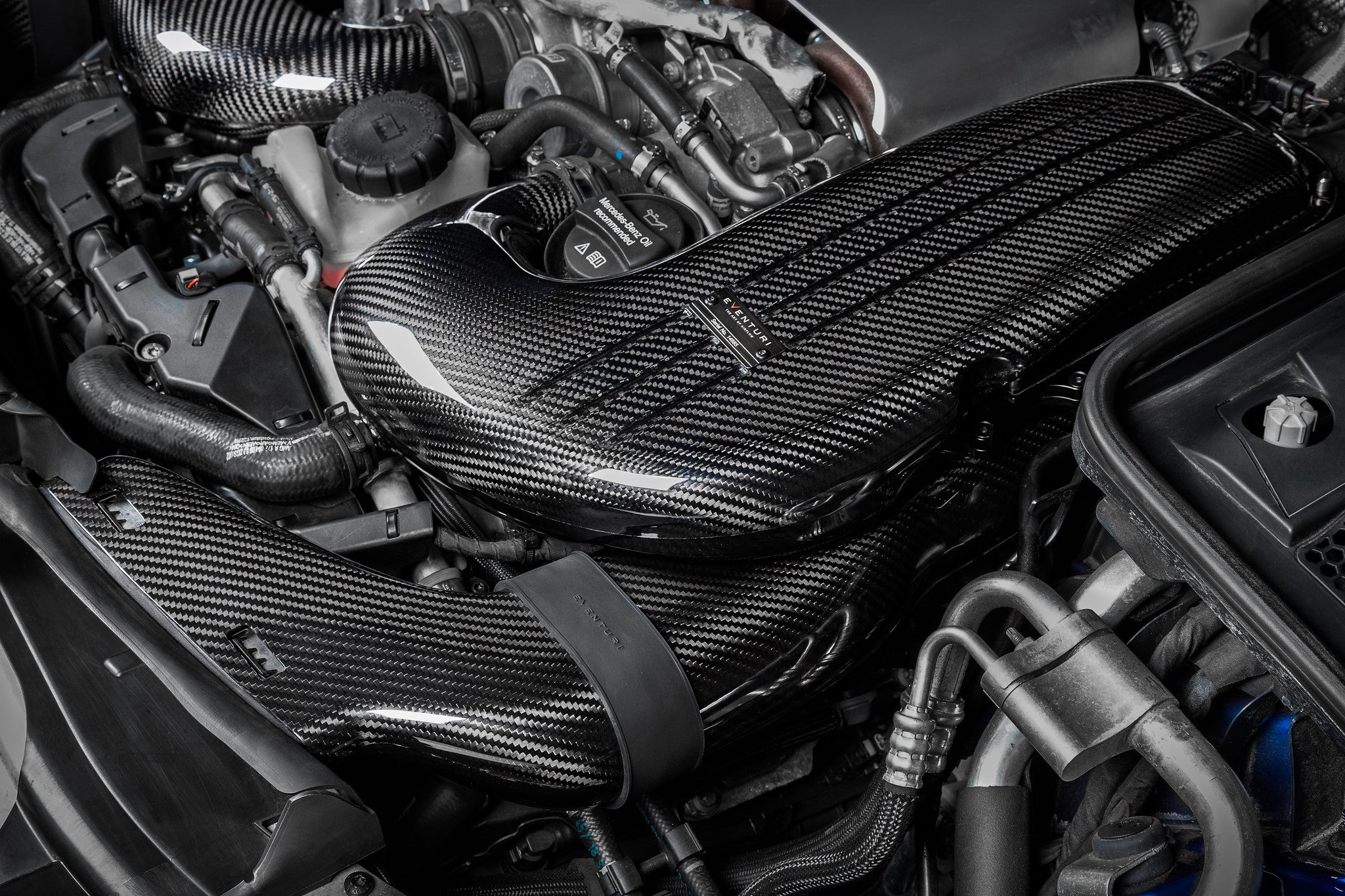 Carbon fiber intake system installed in engine bay with curved ducts and airbox assembly - Eventuri intake for Mercedes-Benz C63