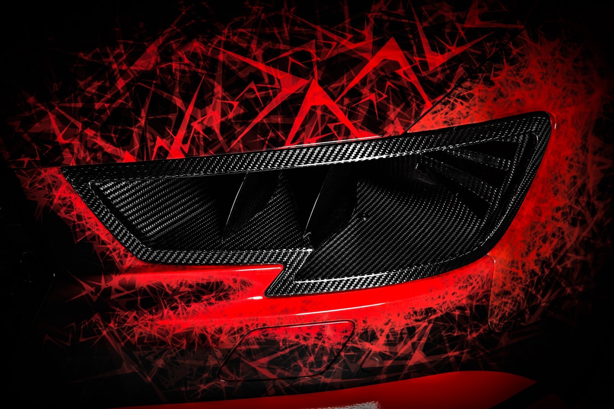 Black carbon fiber headlamp duct with angular vents against dramatic red and black geometric artistic background - Eventuri headlamp race duct for Audi RS3