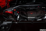 Carbon fiber engine cover with red V-shaped accent installed in engine bay with red hood visible - Eventuri engine cover for Toyota Supra