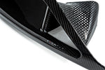 Close-up view of black carbon fiber headlamp duct showing glossy weave pattern and curved aerodynamic design with brand lettering - Eventuri headlamp duct for Toyota Supra