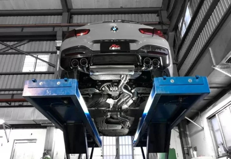 A bottom view of FI Exhaust Valvetronic Exhaust for BMW F20 M140i | 3.0T B58 | 2016-2019 fitted on a grey lifted car