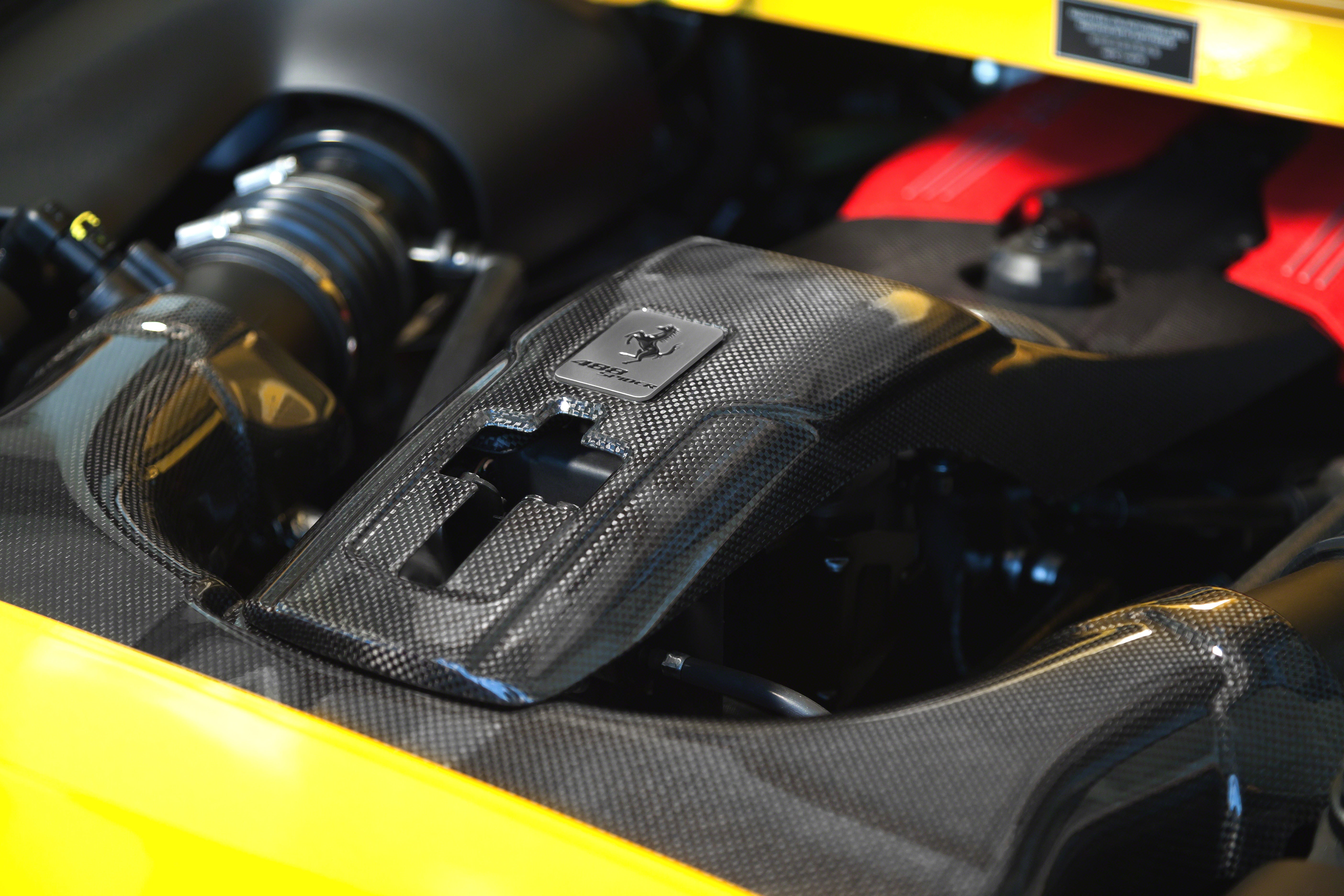 Capristo carbon lock cover fitted in yellow Ferrari 488 engine bay, close view