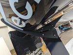 Black carbon fiber rear wing spoiler with adjustable mounting brackets positioned in workshop garage environment - APR Performance rear wing for Universal 