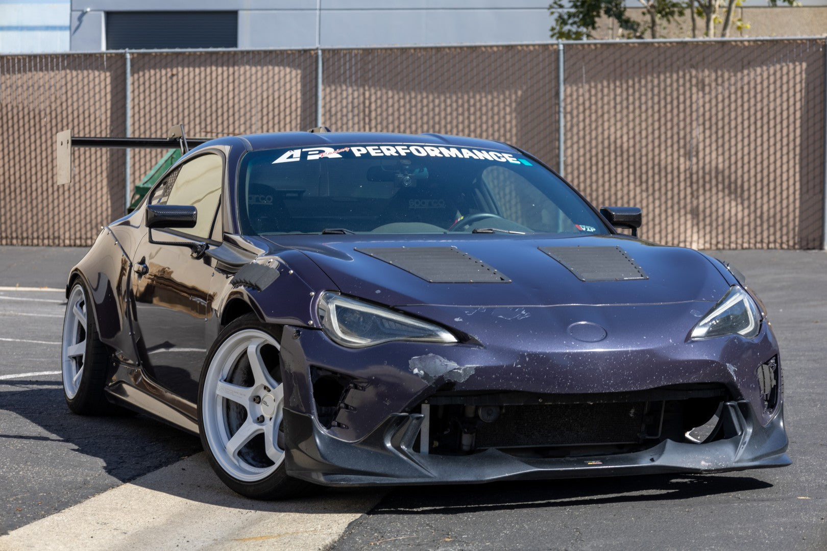 Black carbon fiber aerodynamic side mirrors mounted on dark blue sports car in parking lot setting - APR Performance aero mirror for Scion FRS BRZ GT-86