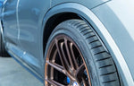 A side close up view of AUTOTECKNIC CARBON FIBER REAR SPLASH GUARDS - BMW F97 X3M | G01 X3 2018+ fitted on a blue car