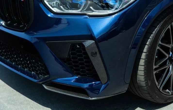 A close up view of a blue car fitted with AUTOTECKNIC PERFORMANCE DRY CARBON SPLITTER SET - BMW F95 X5M 2019+