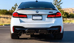 A back view of AUTOTECKNIC DRY CARBON COMPETITION SPORT REAR DIFFUSER - BMW F90 M5 2017+ fitted on a white car outside on the road