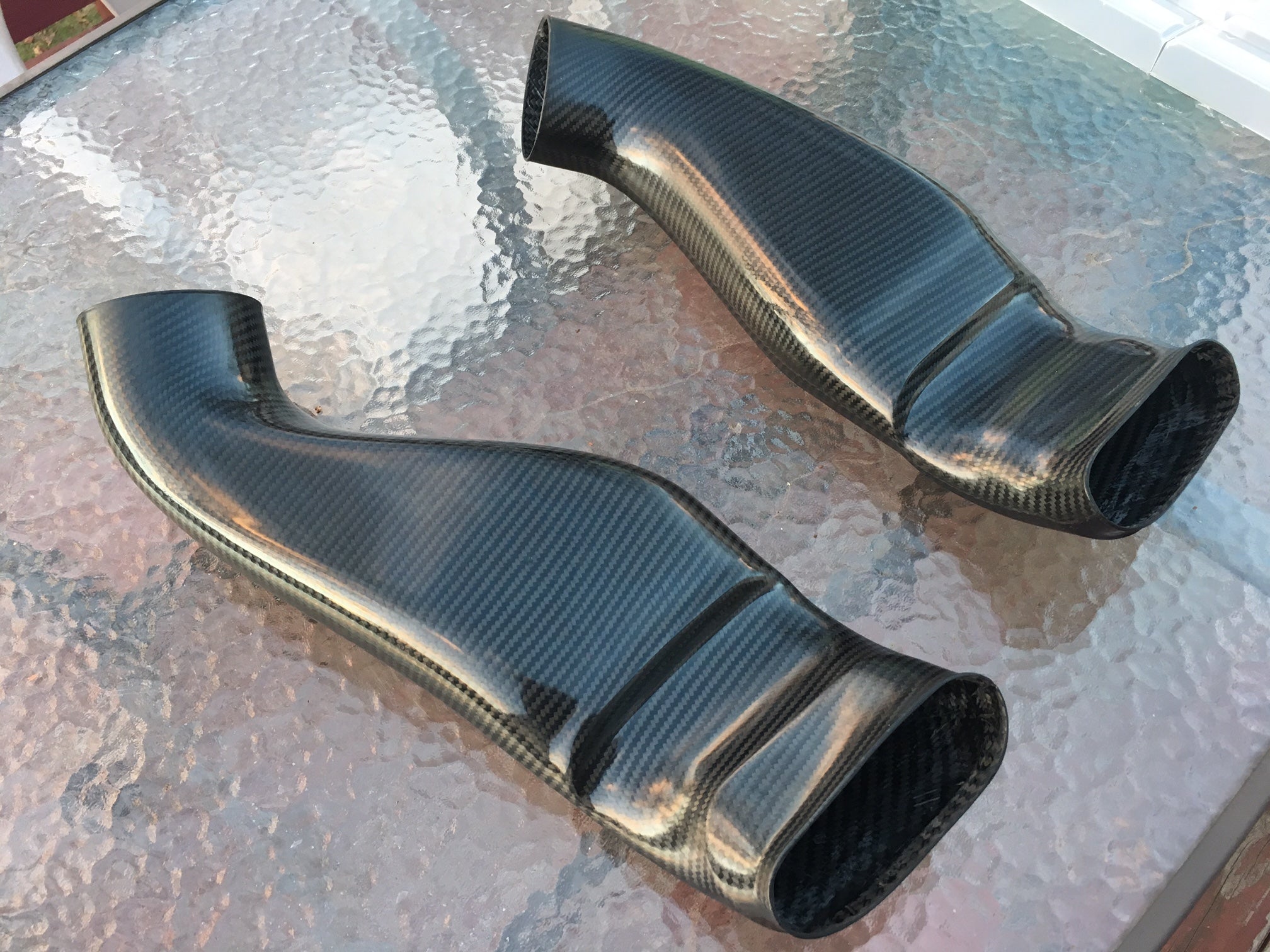 A wide view of RK Autowerks E70 E71 X5M X6M CARBON FIBER INTAKES on a glass table