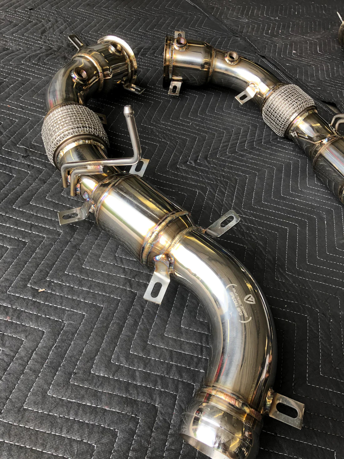 A top view of Valvetronic Designs Free Flow Race Front Pipes on a grey carpet (for Mclaren 540C/570/600LT).