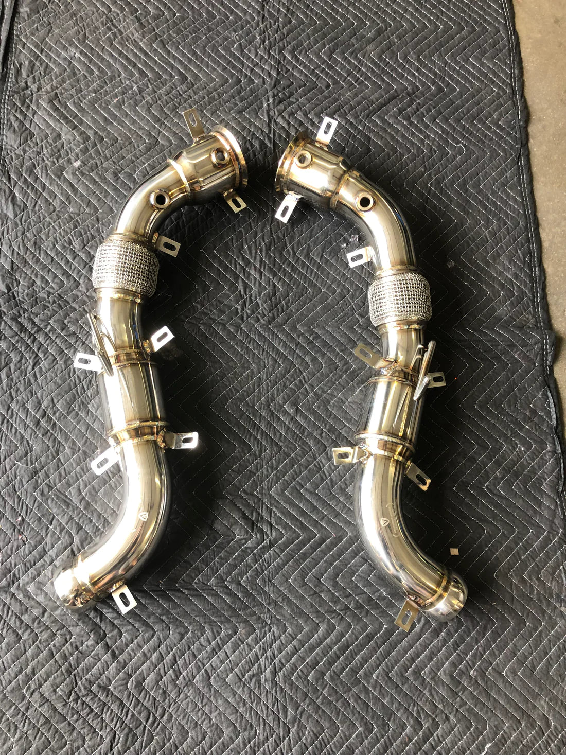 A wide top view of Valvetronic Designs Free Flow Race Front Pipes on a grey carpet (for Mclaren 540C/570/600LT).