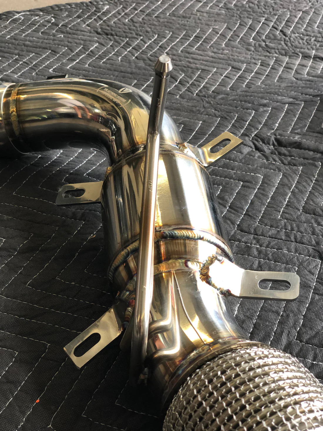 A close view of Valvetronic Designs Valved Sport Exhaust System's free flow front pipes on a grey carpet (for Mclaren 570S / 620R).