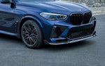 A front side view of a blue car fitted with AUTOTECKNIC PERFORMANCE DRY CARBON FRONT LIP SET - BMW F95 X5M 2019+ on the road