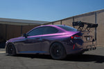 Black carbon fiber rear wing with adjustable endplates installed on purple BMW M2 showing aggressive aerodynamic profile - APR Performance wing for BMW G42 M240i G87 M2