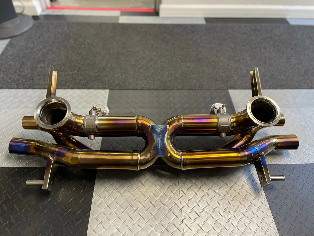 A back overview of Valvetronic Designs Valved Sport Exhaust System (for Audi R8 V10 / Lamborghini HuracanF1) on the ground with black and white and tiles.