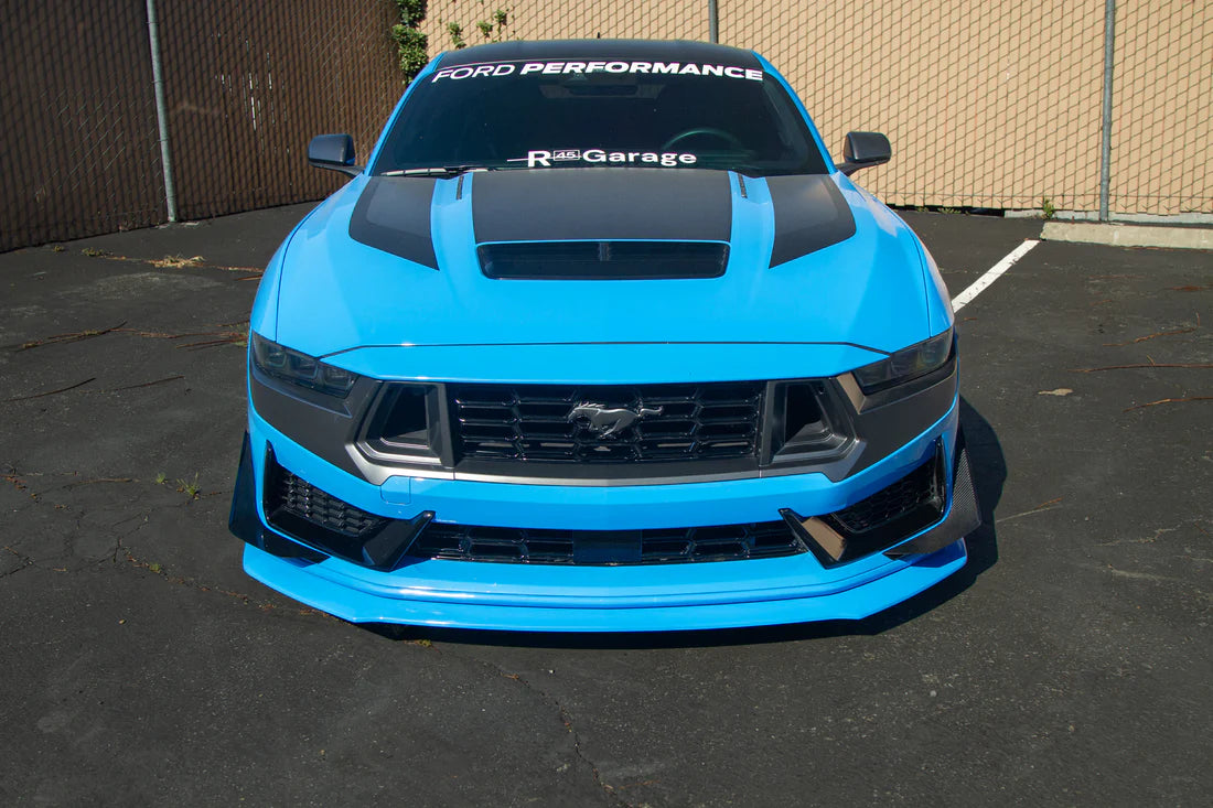 A front wide view of APR Performance Front Bumper Canards for Ford Mustang S650 Dark Horse 2024+ fitted on a blue car on the ground