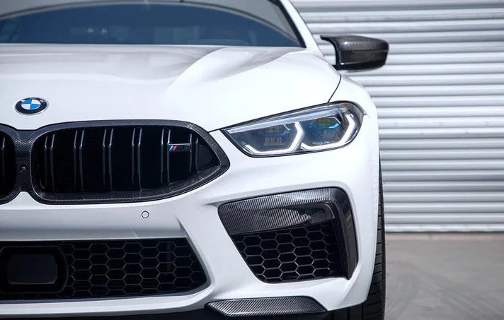 A close up view of a white BMW fitted with AUTOTECKNIC PERFORMANCE DRY CARBON SPLITTER SET - BMW F9X M8 2019+