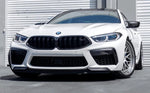 A front view of a white BMW on the road fitted with AUTOTECKNIC PERFORMANCE DRY CARBON SPLITTER SET - BMW F9X M8 2019+
