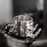 A close up view of RK Autowerks F90 F92 M5 M8 BILLET METHANOL NOZZLE ADAPTERS on a hand with black gloves